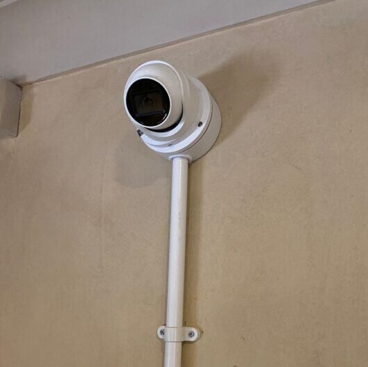 White CCTV camera with conduit for cabling
